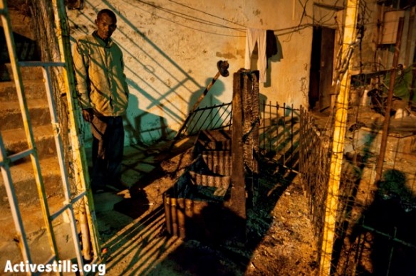 Asylum seeker looking at a couch burned in the South Tel Aviv attack